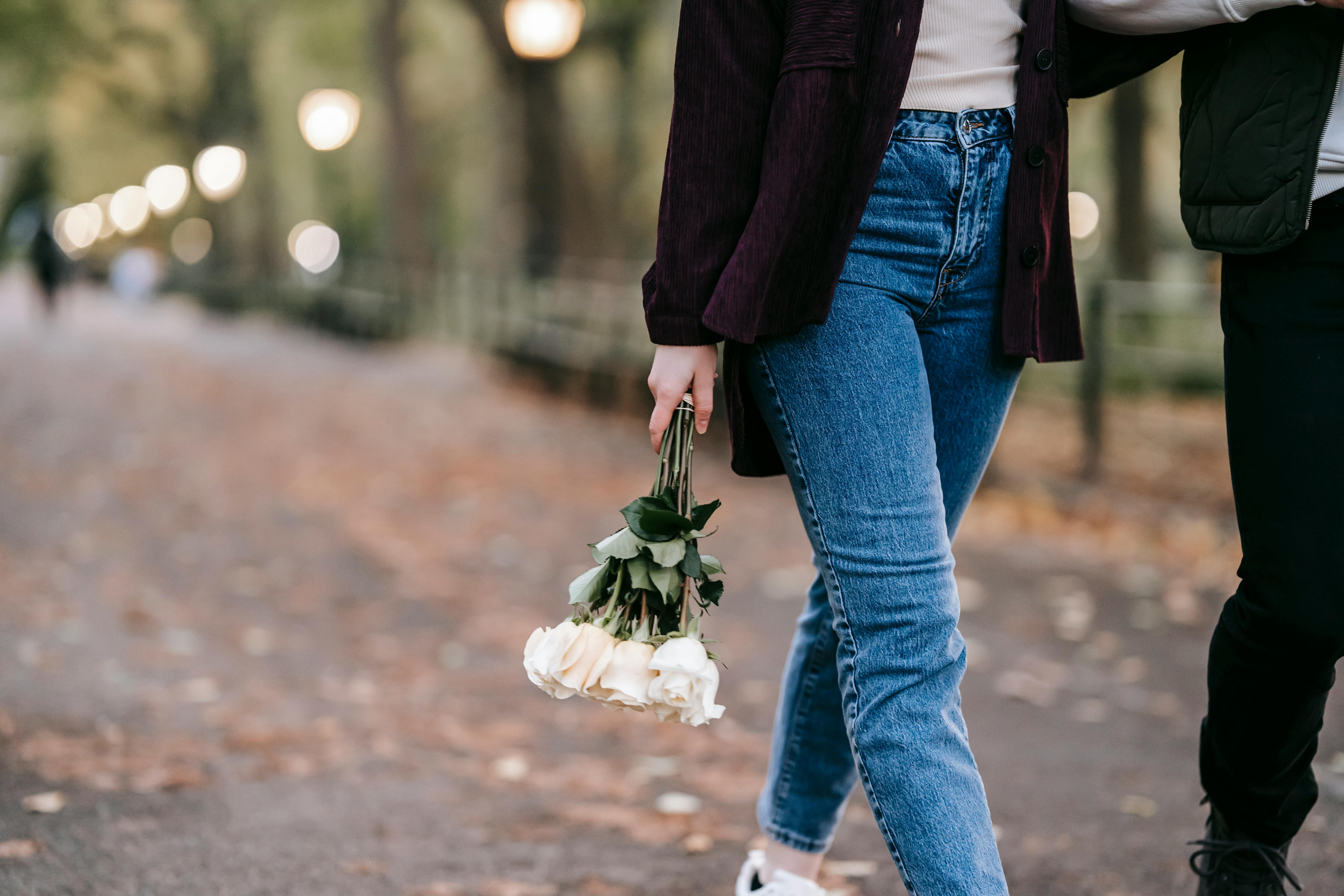 para idąca kobieta w ręce trzyma bukiet białych tulipanów